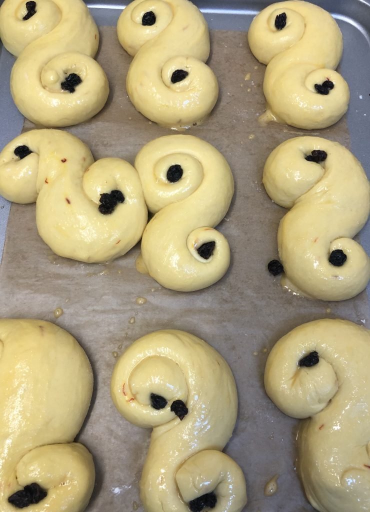 Saffron buns decorated with raisins waiting to be baked